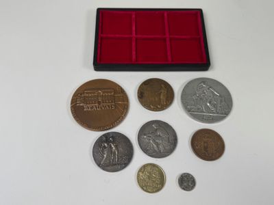 un assortiment de pièces de monnaie et un plateau à pièces posés sur une surface blanche