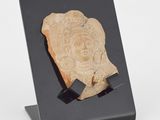 un gros plan d'une plaque en pierre sur laquelle est représenté un visage