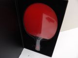 a red ping pong paddle in a black box