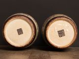 two brown and white vases sitting on top of a wooden table