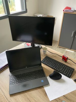 un bureau sur lequel se trouvent un ordinateur portable, un clavier, une souris et un écran