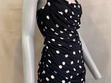 Le mannequin porte une robe noire à pois blancs.
