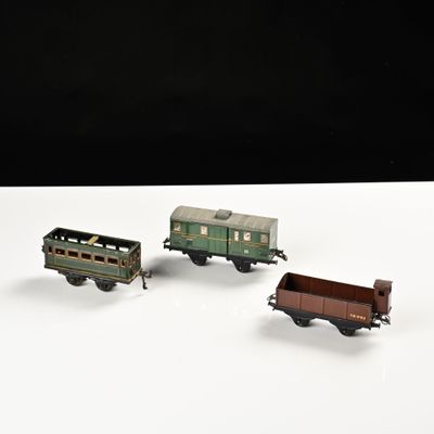 trois petits trains miniatures posés sur une surface blanche, sur fond noir