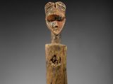 une vieille figurine en bois sur laquelle est représenté un visage