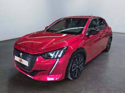 Une voiture rouge est garée dans une grande pièce au sol noir.