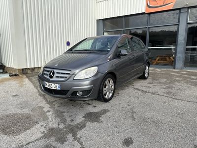 une Mercedes Classe B grise garée devant un immeuble