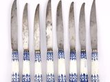 four knives are lined up in a row on a white surface