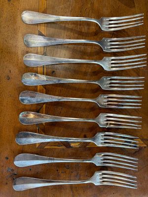 a lot of forks that are on a wooden table
