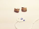 two pairs of gold earrings with a price tag on a white surface