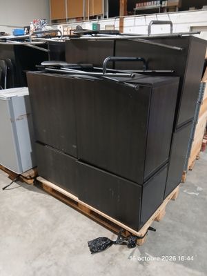 un tas d'appareils électroménagers noirs posés sur une palette dans un entrepôt
