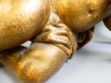une statue en or représentant une personne allongée sur une surface blanche