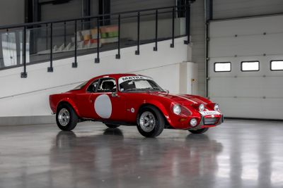 une voiture rouge avec un point blanc sur le côté, garée dans un garage