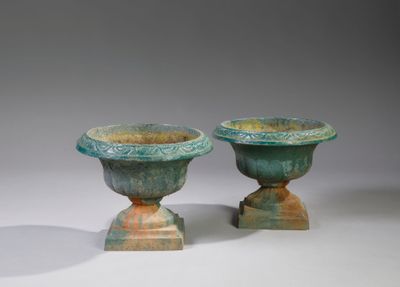 deux vases verts posés l'un sur l'autre sur une surface blanche