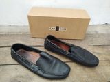 une paire de chaussures de conduite en cuir noir pour homme devant une boîte en carton