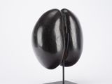 sculpture of a black egg on a black stand on a white background