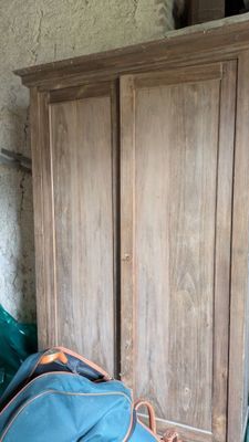 un sac bleu posé par terre à côté d'une armoire en bois