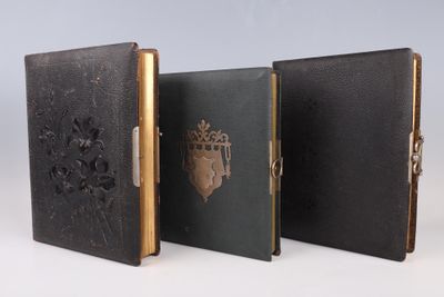 trois livres en cuir noir, avec des bordures dorées et une couronne sur la couverture