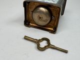 a small key sitting next to a small metal clock