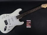 a white electric guitar with a signed picture on it