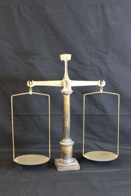 une vieille balance en laiton sur laquelle reposent deux plateaux vides