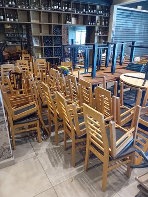 tables and chairs are lined up in a room with shelves full of wine bottles