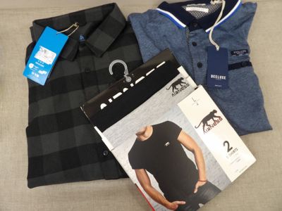 Deux chemises pour homme, un polo et un pantalon sont posés sur un canapé.