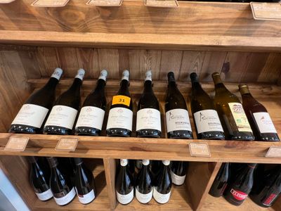 Des bouteilles de vin sont alignées sur une étagère en bois dans un caviste