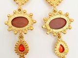 a pair of gold earrings with red and orange stones