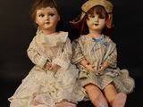 two dolls sitting next to each other on a black surface