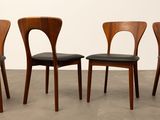 three wooden chairs with black leather upholstered seats in front of a white wall
