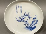 two blue and white plates with flowers on them sitting on a table