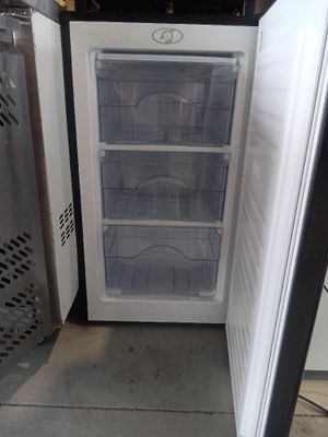 a small refrigerator that is open on the concrete floor