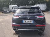 the rear end of a black car parked in a parking lot