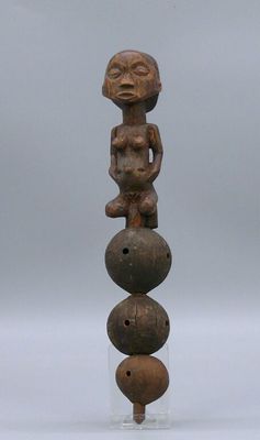 a wooden sculpture of a man sitting on top of three balls