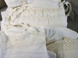 une pile de vêtements blancs posée sur un lit
