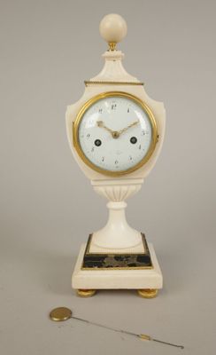 a small white clock with a gold trim on a stand