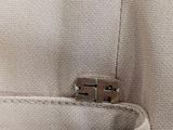 the pocket of a pair of white pants with a metal clasp