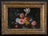 un tableau représentant des fleurs, dans un cadre doré, sur fond noir