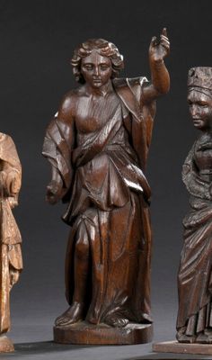 trois figurines en bois sculptées représentant des femmes et un homme, posées sur une table