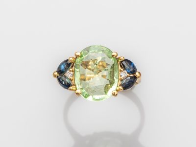 un gros plan d'une bague ornée d'une pierre verte entourée de saphirs bleus