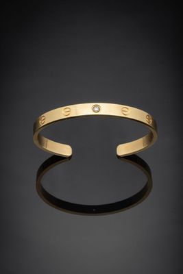 un bracelet manchette en or orné d'un diamant au centre