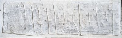 a stone plaque with a cross on it on the side of a building