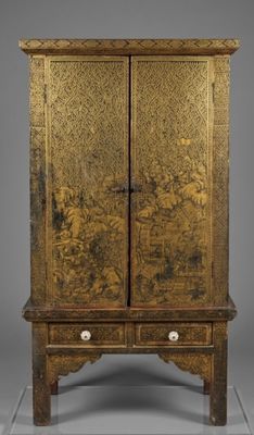 an antique wooden cabinet with gold paint on the doors and drawers
