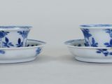 une paire de tasses et soucoupes bleues et blanches posées sur un fond blanc