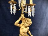 a gold statue of a boy holding a candelab