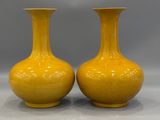 pair of yellow vases sitting on top of a white table