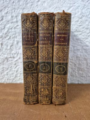 three old books sitting on top of a wooden table