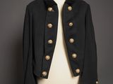 une veste noire à boutons dorés posée sur le torse d'un mannequin