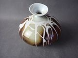 a brown and white vase sitting on a table