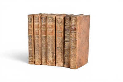 trois vieux livres sont empilés sur une surface blanche